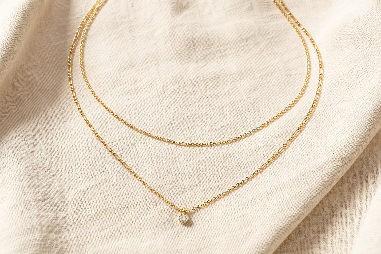 Layered gold chains on warm linen